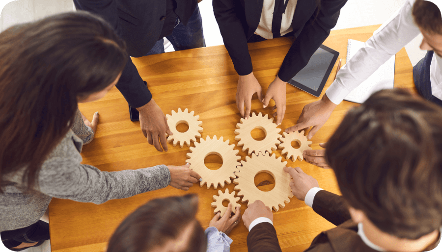 mehrere Menschen bauen ein Zahnrad zusammen