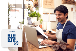 Mann mit Schürze vorm Laptop